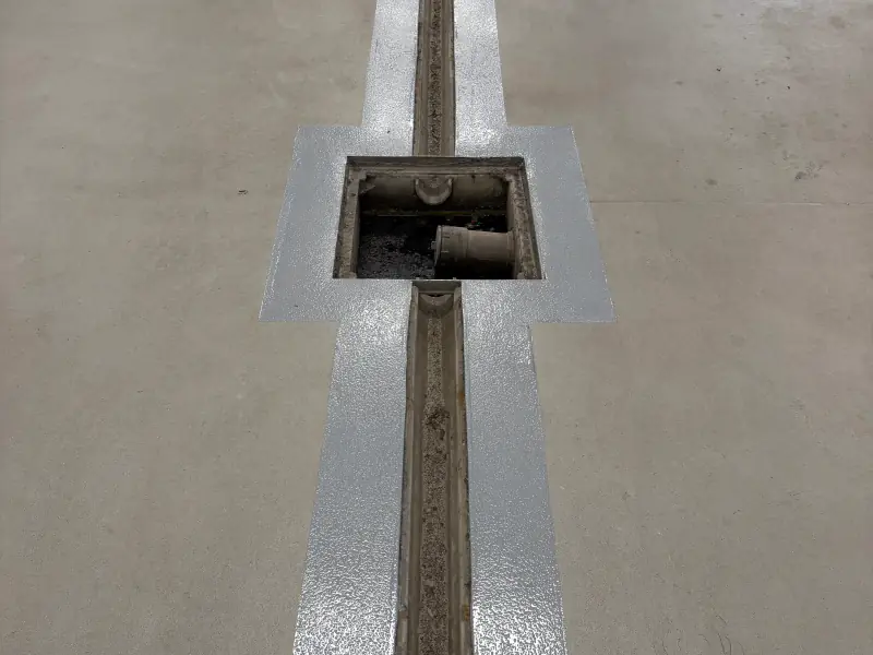Drain de tranchée et regard revêtus d’époxy gris dans un plancher de garage commercial