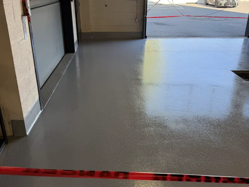 Plancher époxy uni gris devant une porte commerciale